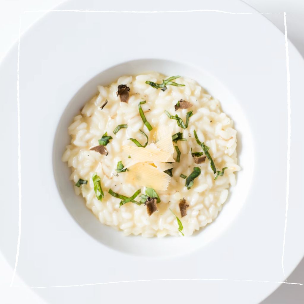 Elegantes Pfeilkresse-Risotto mit Ziegenkäse und karamellisierten Birnen auf weißem Teller