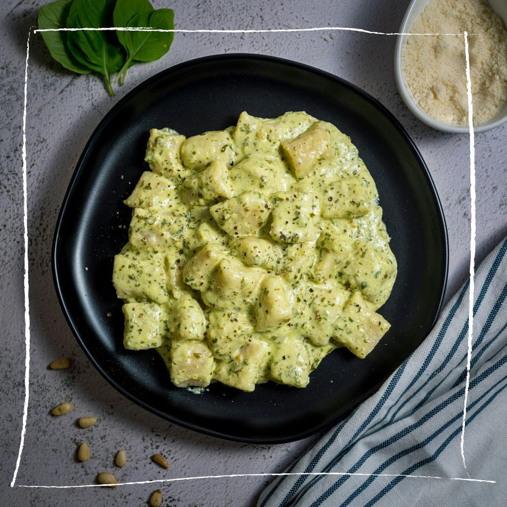 Elegante Gnocchi mit grüner Gundermann-Sahnesauce und gerösteten Haselnüssen auf weißem Teller
