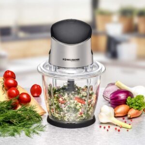 Elektrischer Zerkleinerer mit scharfen Edelstahlklingen, in dem frische Kräuter (Dill) und Nüsse für Pesto zerkleinert werden.